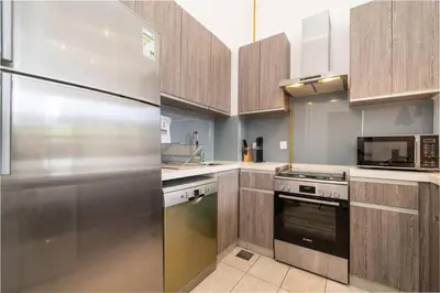 a kitchen with a stainless steel refrigerator and cabinets at Luxury JVC 1BR plus Maids Room Escape with Terrace in Dubai