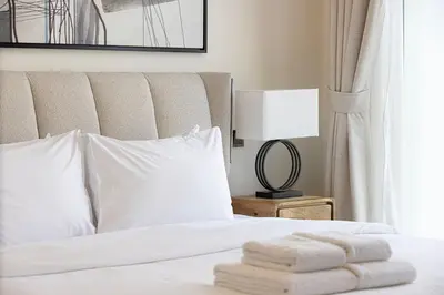 a bed with white sheets and pillows and a lamp at Moon Stays - Opulent 2BR Stay - Sobha Hartland in Dubai