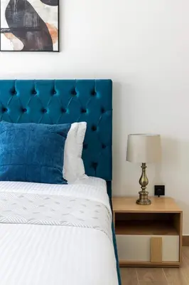 a bed with a blue headboard and a table with a lamp at Frank Porter - Santorini 1, Damac Lagoons in Dubai