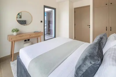 a bedroom with a bed and a table and a mirror at Frank Porter - Santorini 1, Damac Lagoons in Dubai