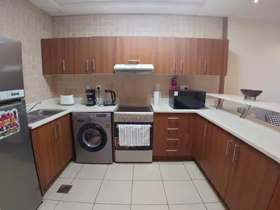 a kitchen with wooden cabinets and a washer and dryer at Spacious 1 BR in Sulafa Tower in Dubai