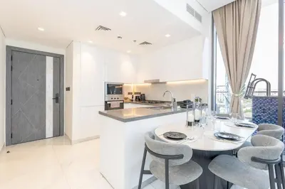 a white kitchen with a table and chairs at Elegant 2BR Apartment Private Pool by Czechin in Dubai