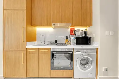 a kitchen with a washing machine and a sink at Fully-Equipped Studio with Pool, Gym & Chic Location in Dubai