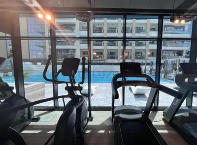 a gym with cardio machines and a swimming pool at Trendy 1BR with a Glimpse of Burj Khalifa, Near Zabeel Stadium, Minutes Drive to Dubai Frame, Binghatti Creek, Al Jaddaf by Deluxe Holiday Homes in Dubai