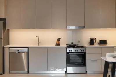 a kitchen with white cabinets and a stove at Waterfront 1BR Apartment in Creek Harbour near Downtown in Dubai