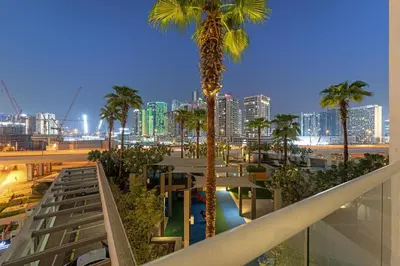 a view of a city from a balcony with palm trees at Spacious 1BR with Balcony and Pool Access in Dubai