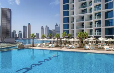 a large swimming pool with chairs and umbrellas and a building at Spacious 1BR with Balcony and Pool Access in Dubai