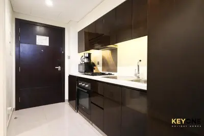 a kitchen with black cabinets and a black door at Majestine Living Stylish Studio with Canal View in Dubai