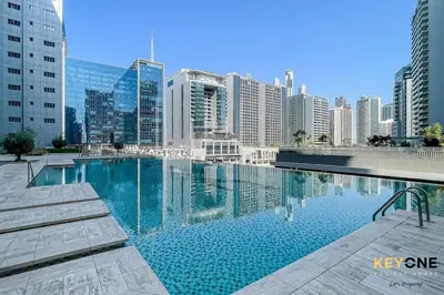a large swimming pool in a city with tall buildings at Majestine Living Stylish Studio with Canal View in Dubai