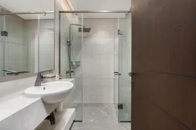 a bathroom with a sink and a glass shower at Samaya Holiday Homes - Modern Luxe Apartments - Nobles Tower in Dubai