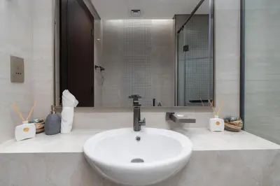 a bathroom with a white sink and a mirror at Samaya Holiday Homes - Modern Luxe Apartments - Nobles Tower in Dubai
