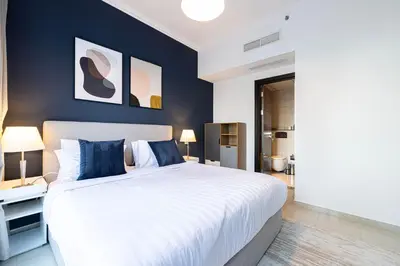 a bedroom with a large white bed with blue walls at Modern 1BR Apt With Access to Jacuzzi, Sauna & Pool in Dubai