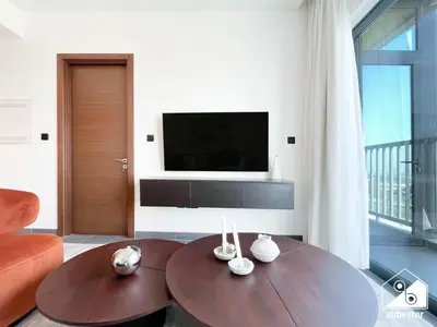 a living room with a table and a television at Modern 1B Luxury , Scenic City Balcony, Pool & Gym in Dubai