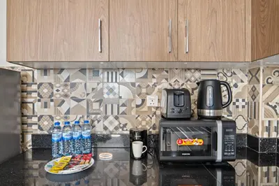 a kitchen counter with a microwave and water bottles at Golden Woods Escape Near Marina & JBR in Dubai