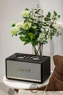 a speaker sitting on a table next to a vase of flowers at Stylish 1 bedroom in Pinnacle, Dubai Hills in Dubai
