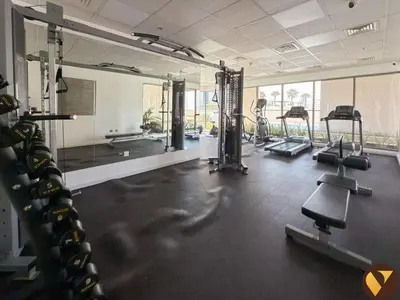 a gym with a bunch of treadmills and mirrors at Vogue Jeewar JVC near Circle Mall, One Bedroom Apartment with Balcony and Park view, Access to all Amenities in Dubai