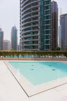 a large swimming pool in front of a tall building at Royal suites LIv Marina views in Dubai