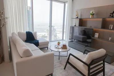 a living room with white furniture and a large window at Royal suites LIv Marina views in Dubai