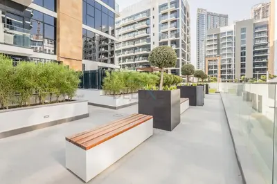 a bench on a sidewalk with buildings in the background at Close to Meydan Racecourse and Ras Al Khor Wildlife Sanctuary, And a Quick Drive to Downtown Dubai and the Iconic Burj Khalifa - Azizi Riviera 44, Meydan by Deluxe Holiday Homes in Dubai