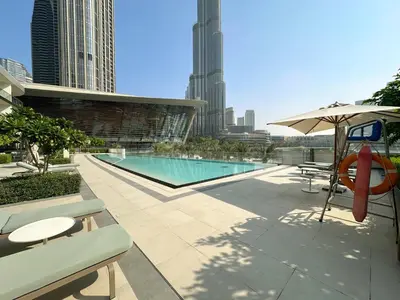 a swimming pool with an umbrella and a table and chairs at VayK - Stunning 2BR Apt with 2 Balconies in Downtown in Dubai