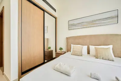 a bedroom with a white bed and a large mirror at Modern 2BR Retreat in JVC with Private Pool Balcony in Dubai