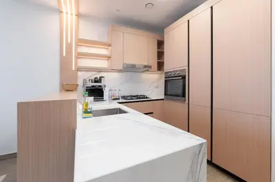 a kitchen with white counter tops and wooden cabinets at Modern Aura Living Chic 1BR Hideaway in JVC in Dubai