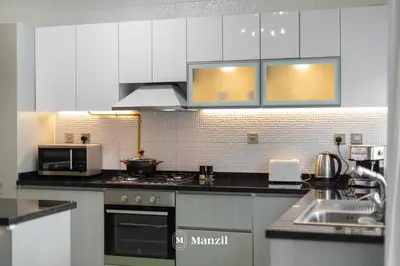 a kitchen with white cabinets and a stove top oven at Luxury 2BR Apartment in Business Bay with Pool, Sauna and Burj Khalifa View in Dubai