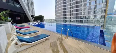 a swimming pool with two lounge chairs next to a building at Luxury 2BR Apartment in Business Bay with Pool, Sauna and Burj Khalifa View in Dubai