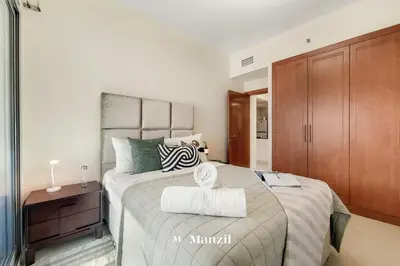 a bedroom with a large bed and a wooden cabinet at Cozy 1BR Apartment in Dubai Marina with City Views in Dubai
