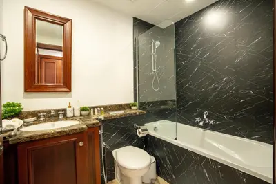 a bathroom with a toilet and a tub and a sink at Zaafaran 5 Full Burj View Downtown Luxury Stay in Dubai