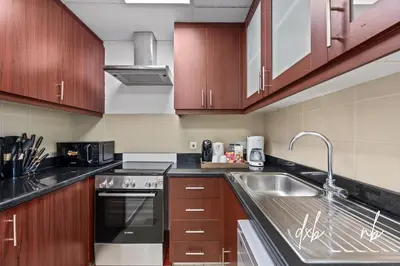 a kitchen with wooden cabinets and a sink at Pistachio Pecan - Sea View - Luxury 1 BR Apartment at JBR Beach in Dubai