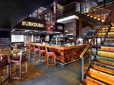 a restaurant with a bar with wooden tables and chairs at JLT Laguna Tower Spacious Studio with Lake View for 4 Guests in Dubai