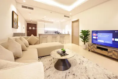 a living room with a couch and a tv at Luxury 1BR at Sterling East , Burj Khalifa Views in Dubai