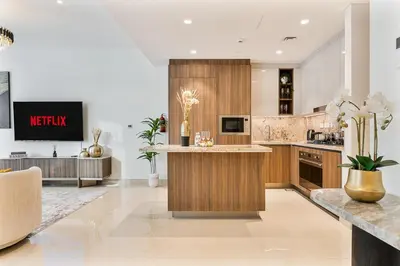 a kitchen with wooden cabinets and a tv on a wall at Deluxe, Elegant - 3BR - DT - Burj Khalifa View in Dubai