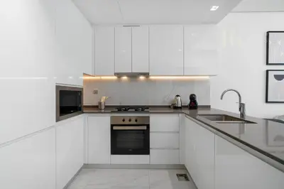 a white kitchen with a sink and a stove at Stylish Living with a Cozy Touch in Dubai