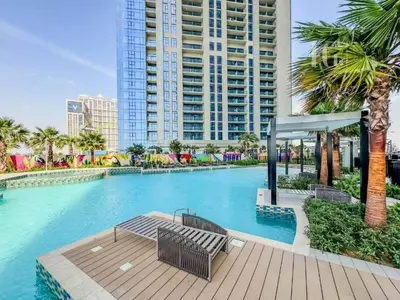 a swimming pool with a bench and palm trees at Charming Studio with Cozy Vibes in Dubai