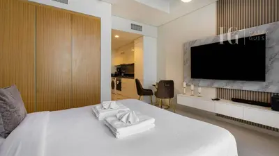 a bedroom with a white bed with a flat screen tv at Charming Studio with Cozy Vibes in Dubai