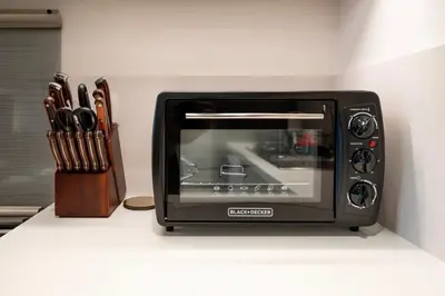 a black toaster oven sitting on a counter next to a knife block at Designer 1 Bedroom Apartments in Dubai Hills Estate in Dubai