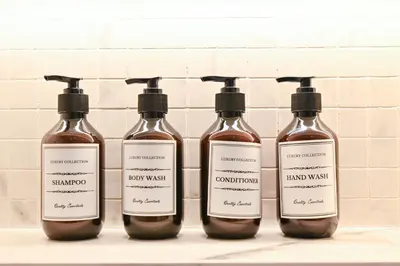 a group of four bottles of liquid on a shelf at Azizi Riviera Gateway - Highest Floor Superior Apartment in Dubai