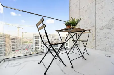 a chair and a table on a balcony at Azizi Riviera Gateway - Highest Floor Superior Apartment in Dubai
