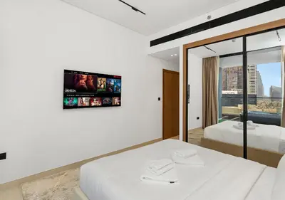 a bedroom with two beds and a tv on the wall at Luxury 1 BR Apartment with Private Jacuzzi in Dubai