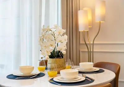 a dining room table with plates and glasses and flowers at Luxury 1 BR Apartment with Private Jacuzzi in Dubai