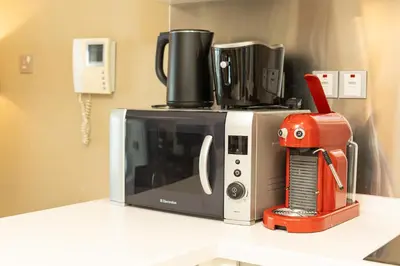 a microwave sitting on top of a counter with a red appliance at PVH - Emaar Fashion Avenue - 1BR Dubai Mall Access in Dubai