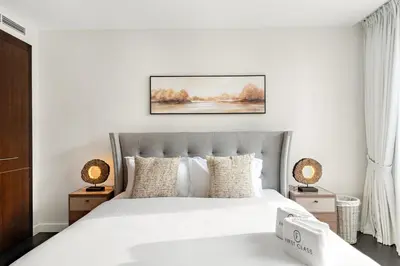 a white bedroom with a large bed with white sheets at FIRST CLASS 2BR Spacious DIFC Living in Dubai