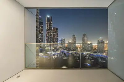 a window with a view of a city at night at FIRST CLASS 1BR Majestic Marina Views in Dubai