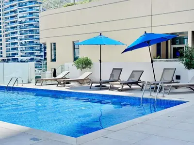 a pool with chairs and umbrellas next to a building at FIRST CLASS 1BR Majestic Marina Views in Dubai
