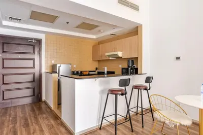 a kitchen with two bar stools and a refrigerator at Stunning lake view 1bedroom apartment in Jlt in Dubai