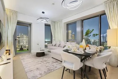 a living room with a white couch and a table and chairs at FIRST CLASS 2BR Burj Views & Classy Comfort in Dubai