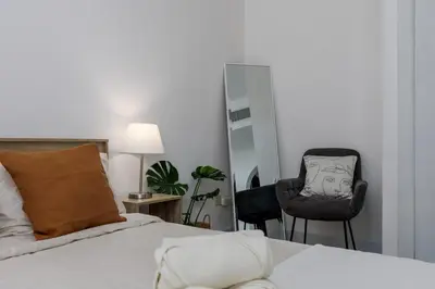 a bedroom with a bed and a chair and a mirror at Waves - Cozy & Fully Furnished Studio in Dubai Sports City in Dubai