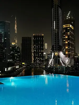 a large blue swimming pool in a city at night at The Haven Burj Khalifa View - 1BR Business Bay with Balcony&Pool in Dubai